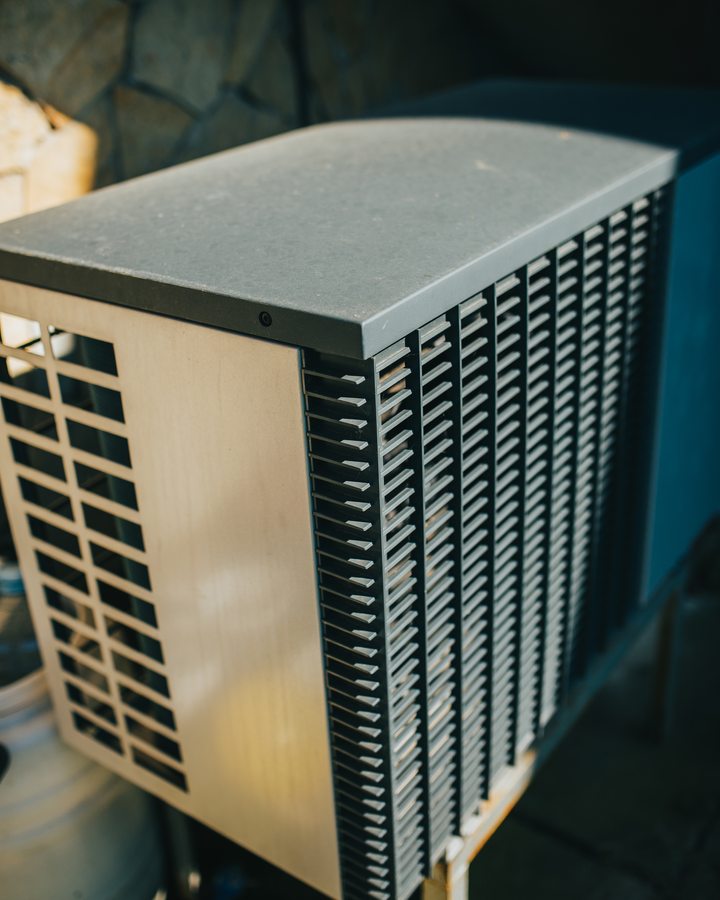 Closed outdoor air-conditioning unit beside a stone wall