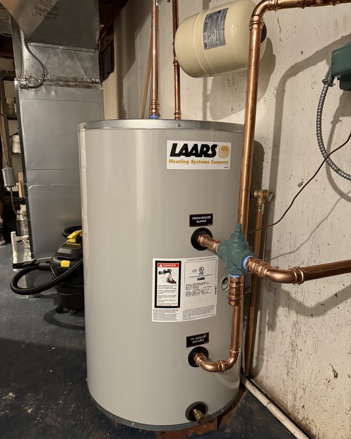 Hot-water storage tank with copper pipe connections in a utility space