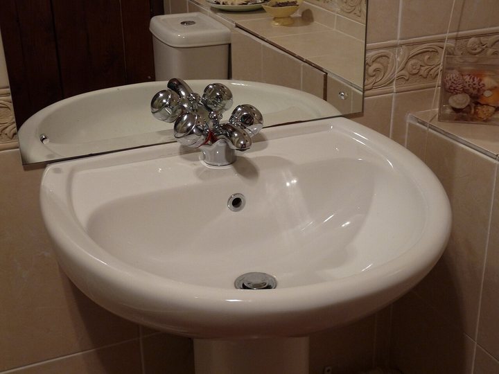 White bathroom basin with chrome cross-handle taps in front of a mirror
