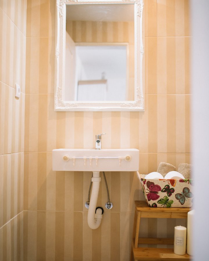 White bathroom basin and chrome faucet against sand-colored tiles
