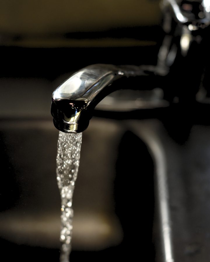 Chrome kitchen faucet with water flowing into a sink