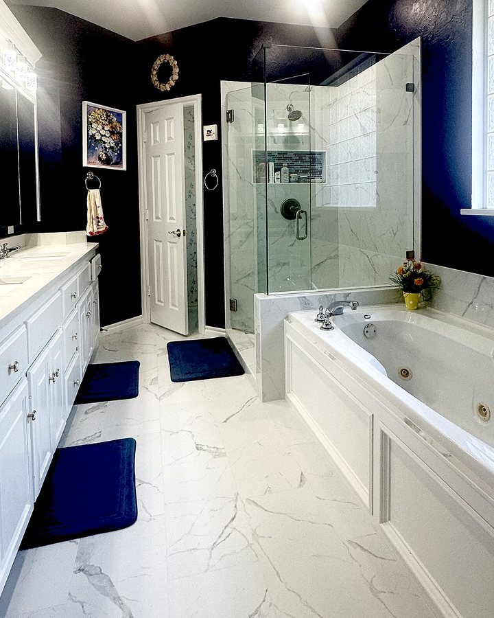White bathtub and glass-enclosed shower beside a vanity in a tiled bathroom