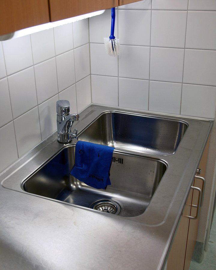 Stainless-steel double kitchen sink with a chrome faucet and white tiled backsplash